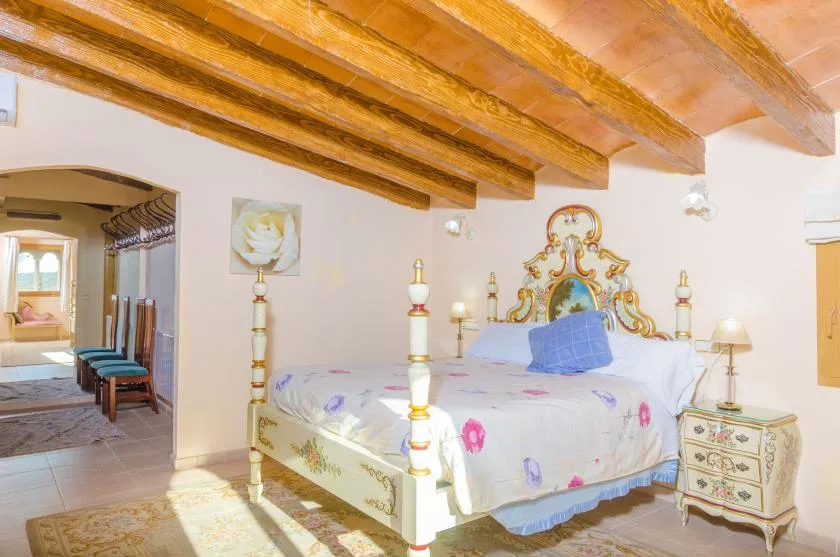 A bedroom with a bed beneath exposed wooden ceiling beams.