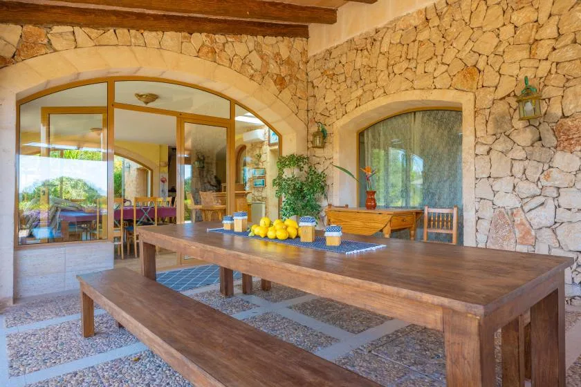 A rustic dining area with a long wooden table and stone walls.