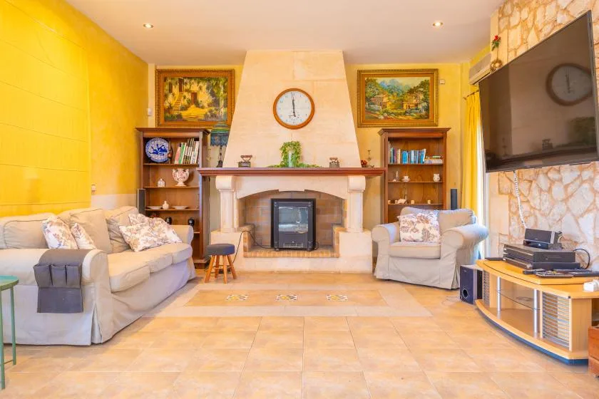 A living room with seating arranged around a fireplace and television.