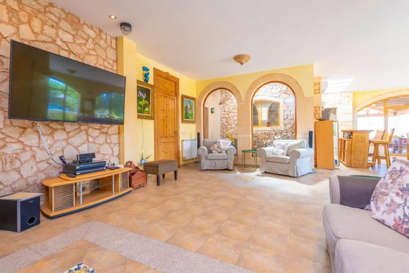A living room with seating and a television beside an arched window.