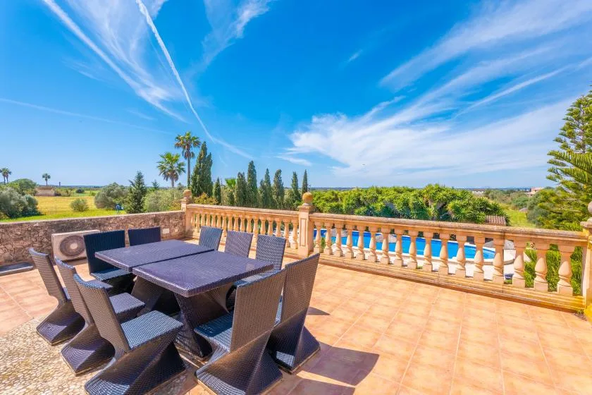 An outdoor terrace has a dining table and seating beside a balustrade.