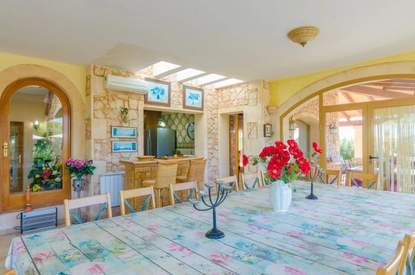 A bright dining area with a long table and a stone-faced bar in the background.