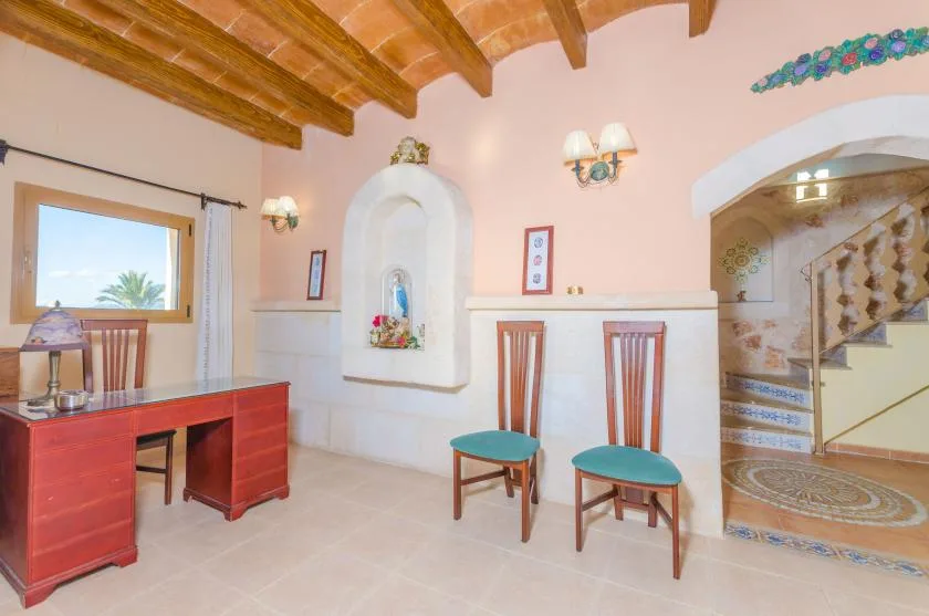 A pink-walled interior has a desk, two chairs, and a staircase.