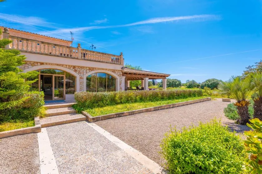 A stone building with arched windows stands beside a landscaped gravel courtyard.