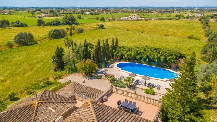 An outdoor pool and patio overlook expansive green fields.