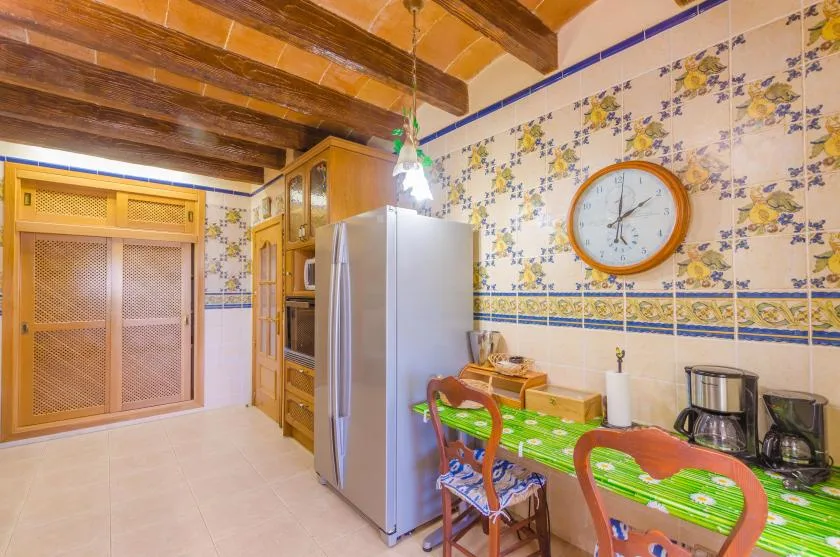 A tiled kitchen with a refrigerator, countertop appliances, and a dining table.