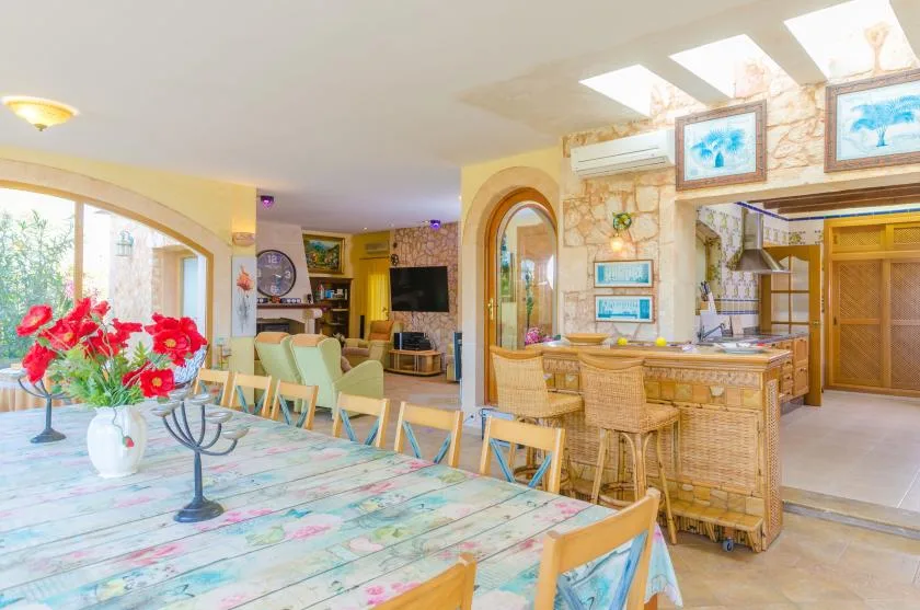 A bright dining and living area with a long table and a bar counter.