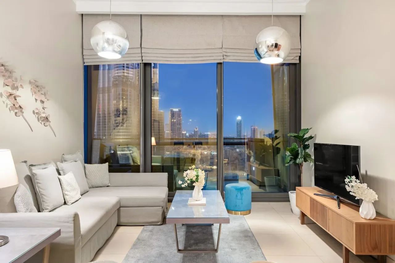 A bright living room with seating facing large windows and a city view.