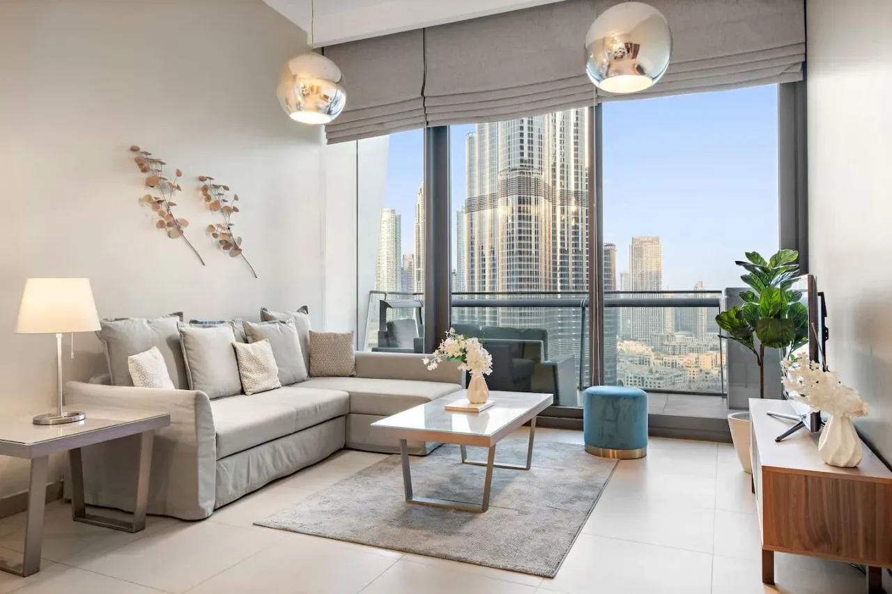 Una sala luminosa con asientos junto a grandes ventanales con vistas a edificios de la ciudad.