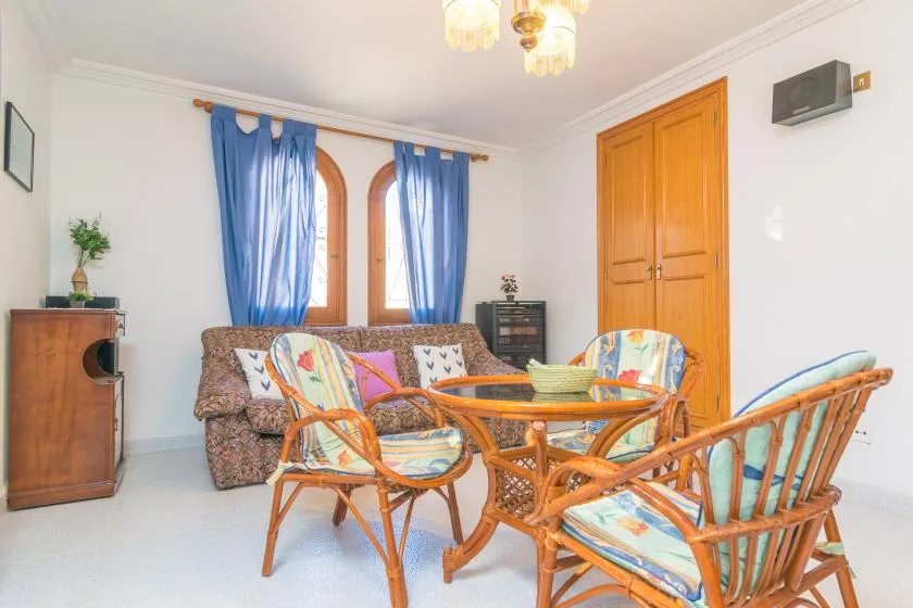 A bright sitting room with wicker seating around a glass-topped table.