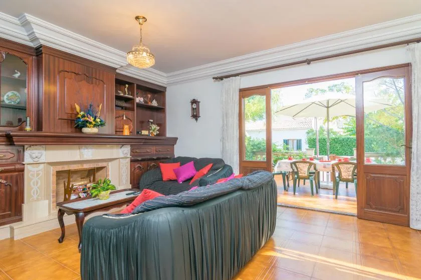 A living room with seating arranged around a fireplace and open doors to a patio.