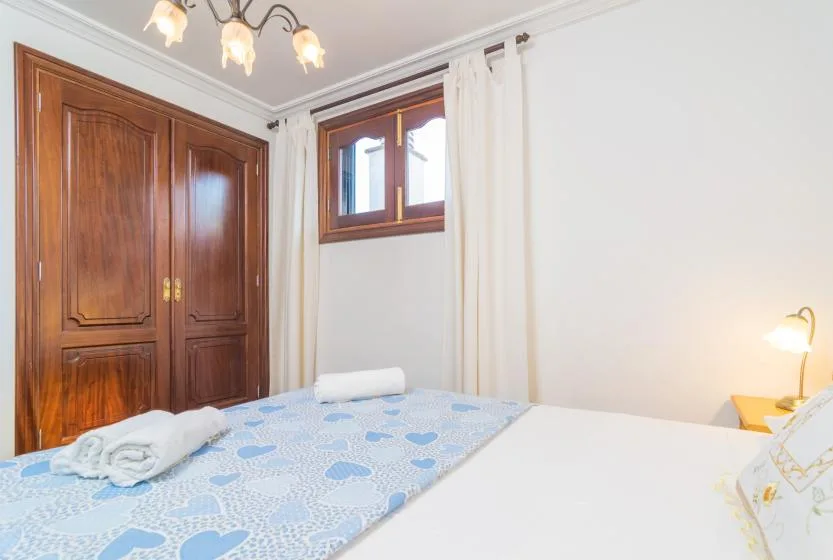 A bedroom with patterned blue bedding, a wooden wardrobe, and a small window.