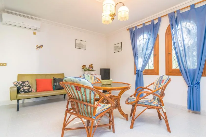 A bright sitting room with wicker seating around a glass-topped table.