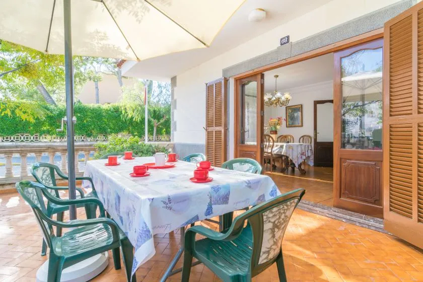 A covered patio with a dining table and chairs opens onto a garden.