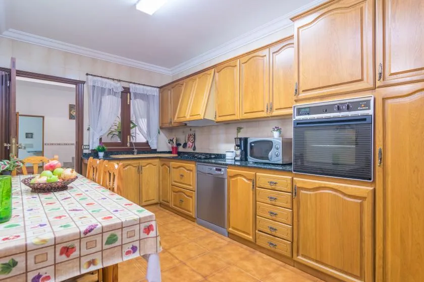 A kitchen with wooden cabinets, appliances, and a dining table.