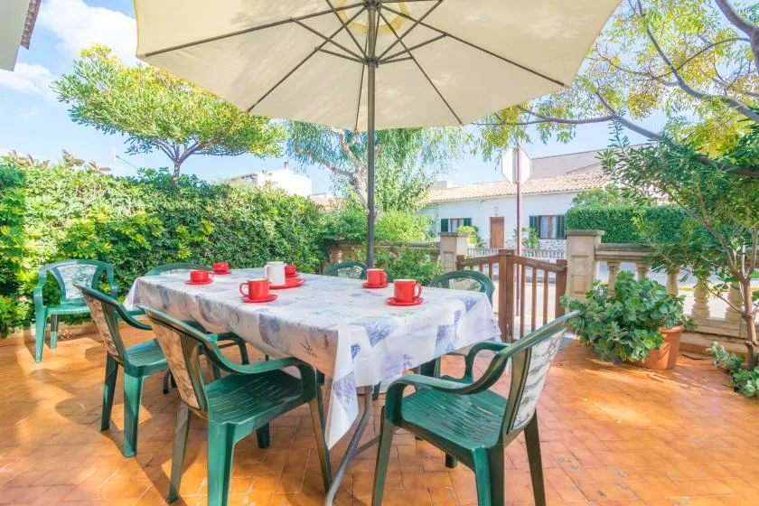 An outdoor dining area with a long table set beneath a large umbrella.