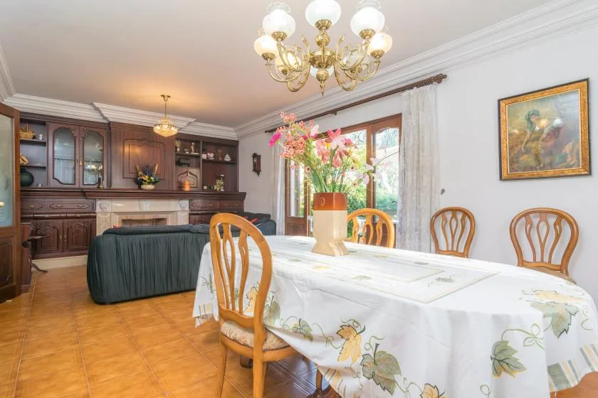 A dining room with a long table, wooden chairs, and a dark wood cabinet.