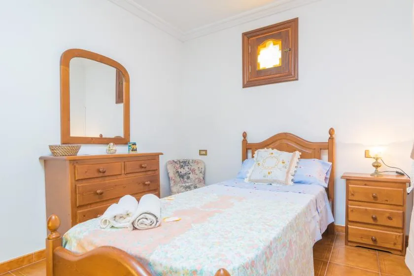 A bedroom with a wooden bed, floral bedding, and a matching dresser.