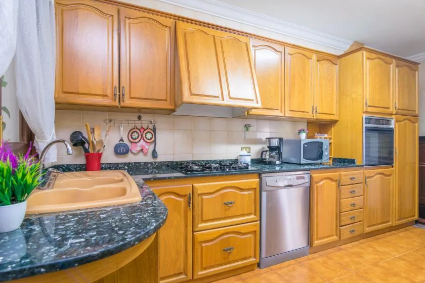 A kitchen with wooden cabinets, dark countertops, and stainless steel appliances.