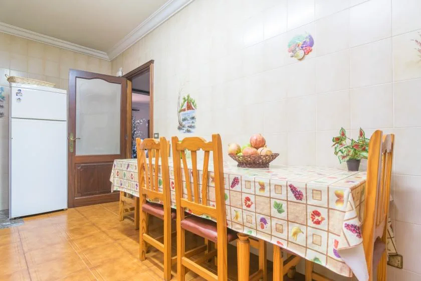 A tiled dining area with a table, wooden seating, and a refrigerator.