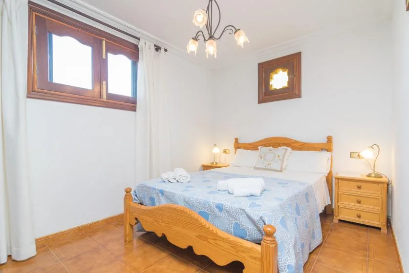A bedroom with a wooden bed, blue bedding, and a bedside table.