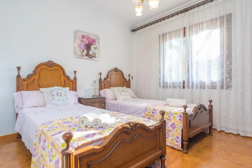 A bedroom with two wooden beds dressed in colorful floral bedding.