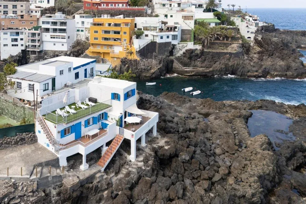 Coastal buildings overlook a rocky shoreline and a small inlet.