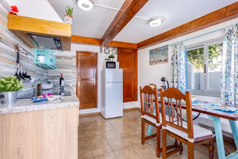 A kitchen and dining area with wooden seating beside large windows.