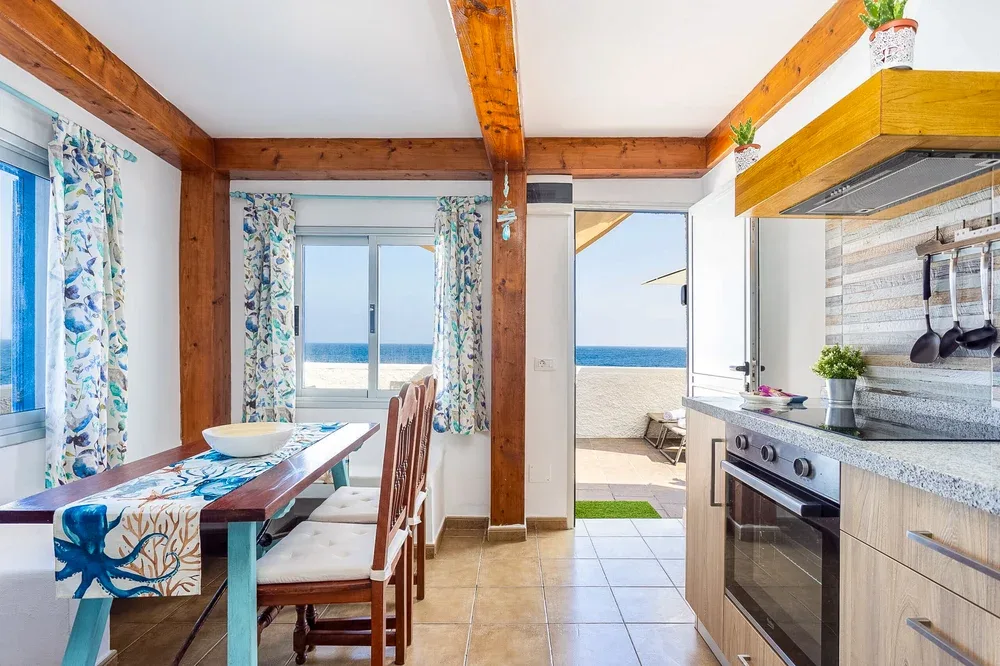 A kitchen and dining area open onto a balcony with a sea view.