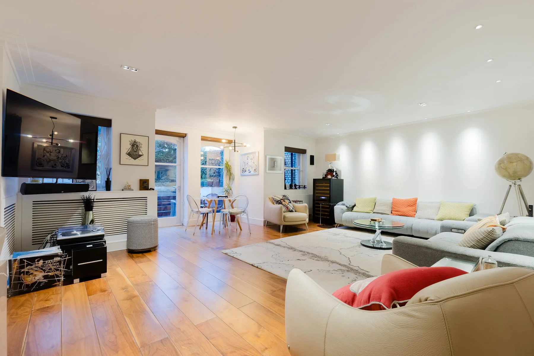 Una sala luminosa con asientos, un televisor y un comedor.