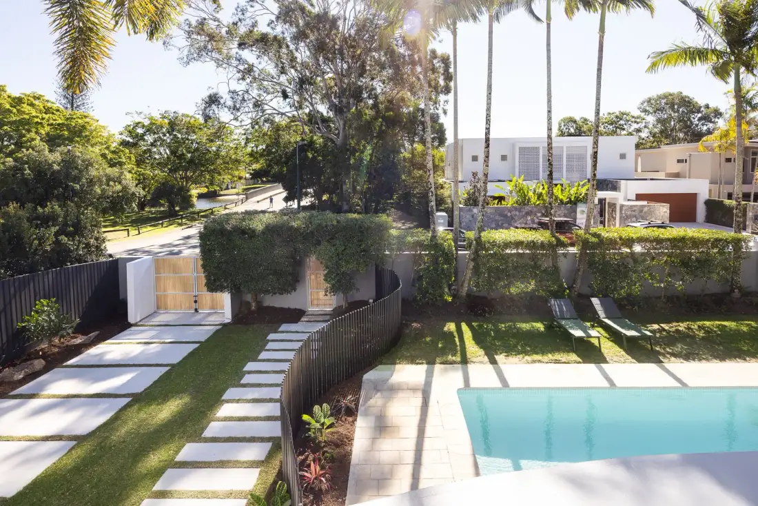 A swimming pool beside a landscaped path and modern residence.