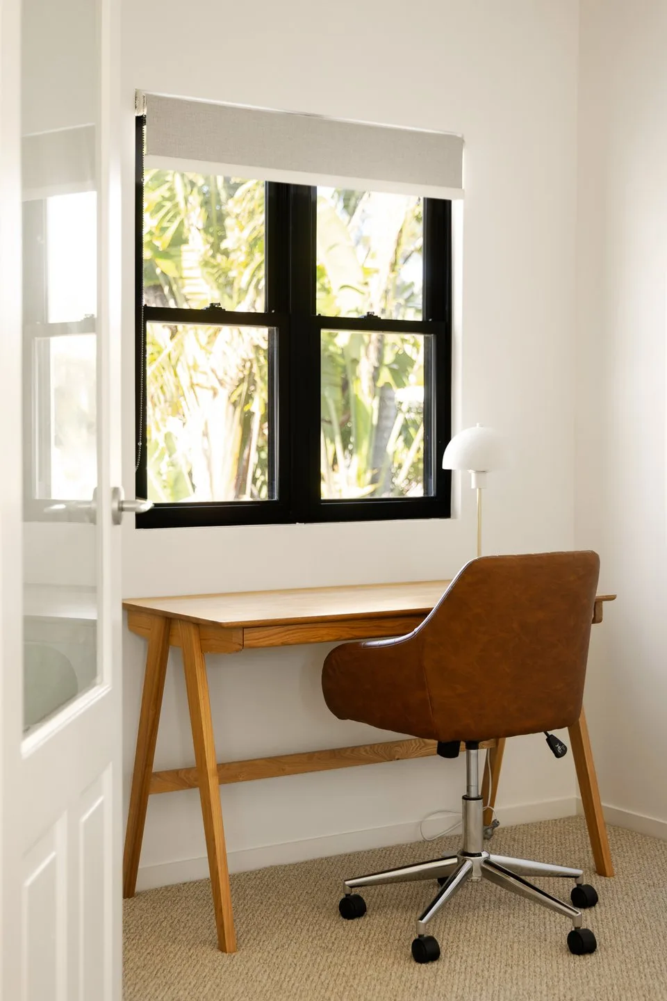 A bright desk area sits beside a window overlooking leafy greenery.