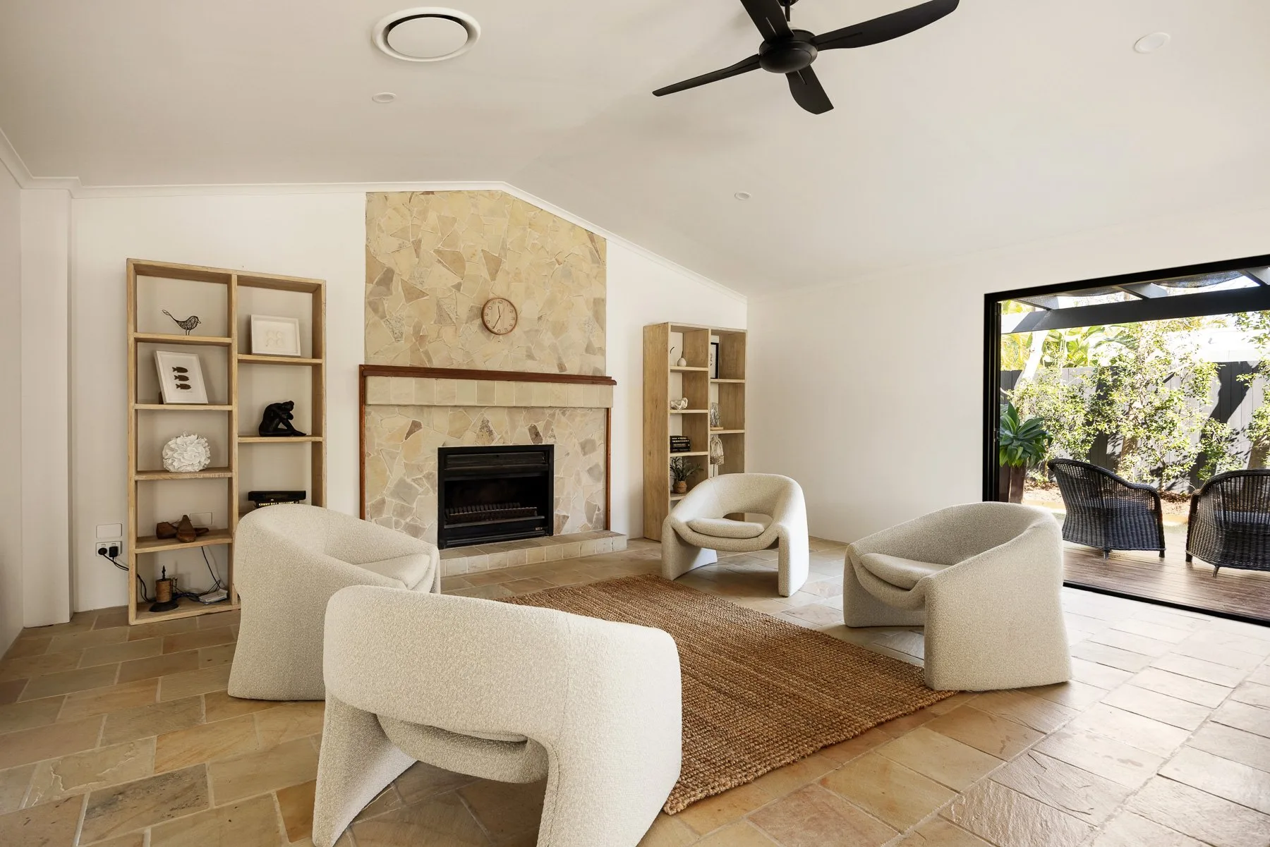 Living room with a fireplace, seating, and an open view to the patio.