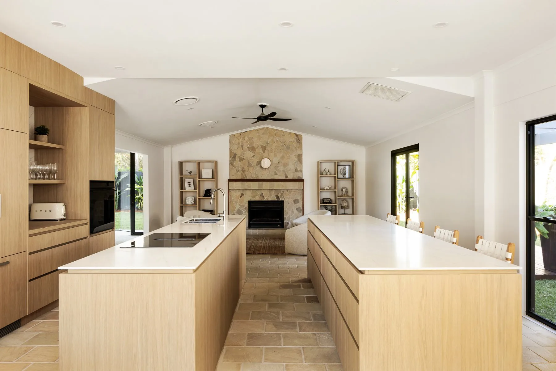 A bright kitchen with two long counters and a fireplace at the far end.