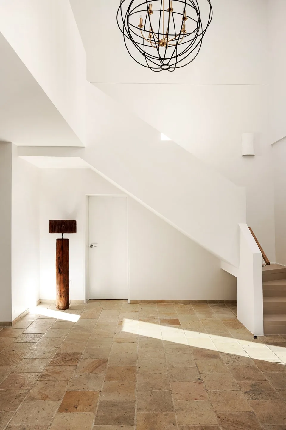 A bright interior entryway with a staircase and sculptural hanging light.