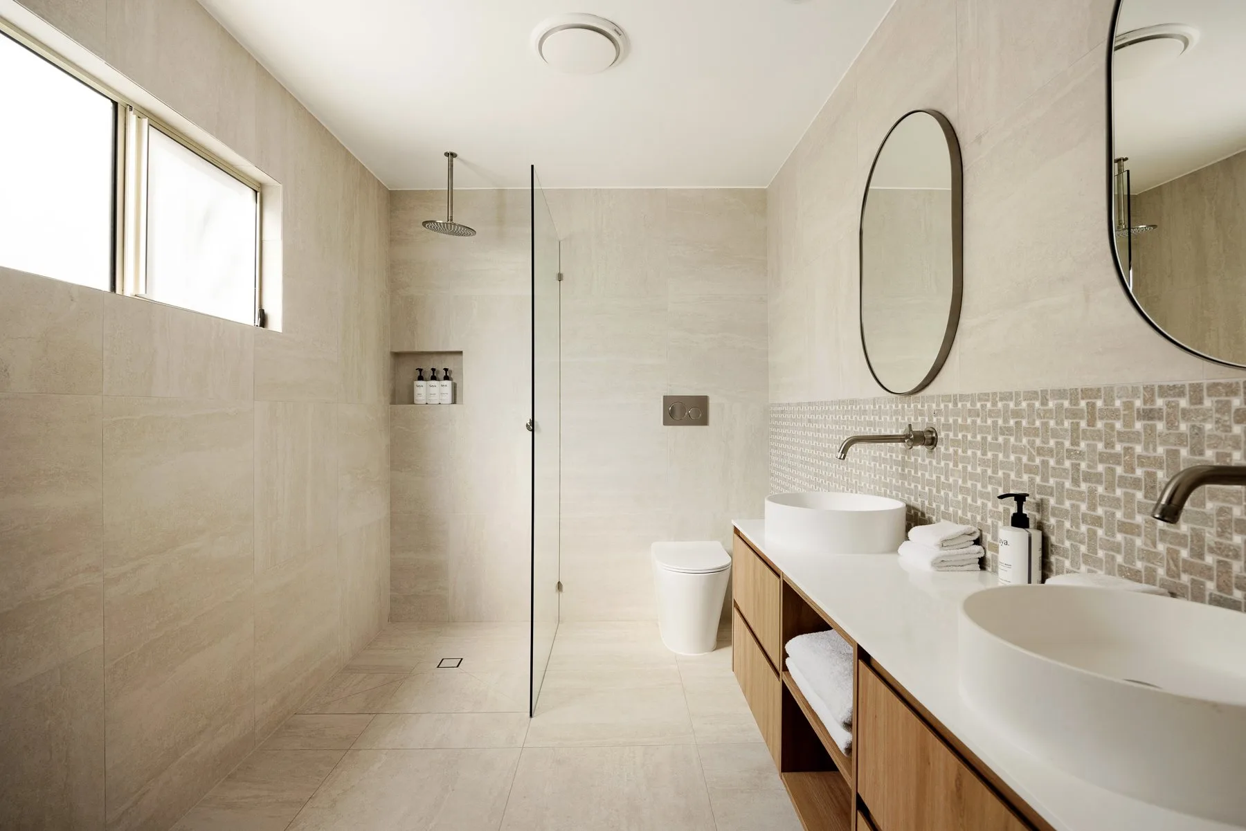 A bright bathroom with a walk-in shower and double sinks.