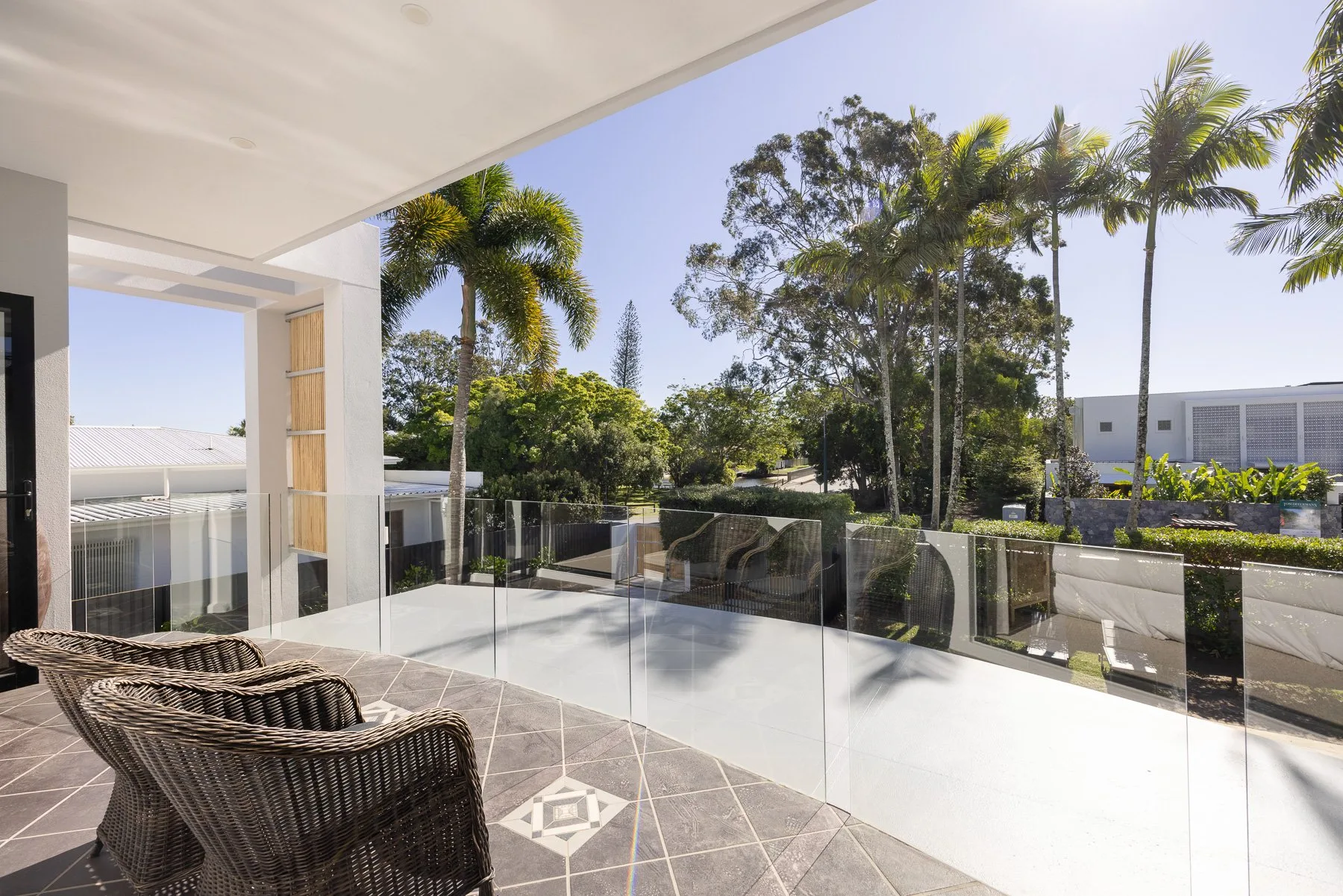 A covered outdoor terrace with woven seating overlooks a garden.