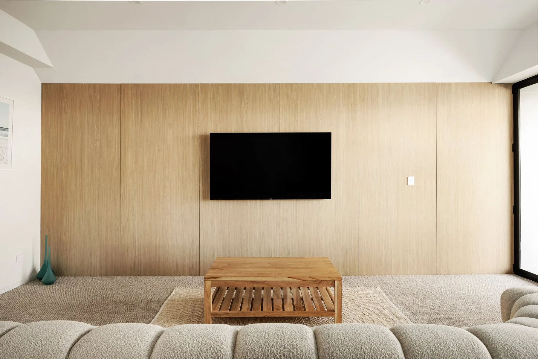 A living room with a wall-mounted television and a low wooden table.