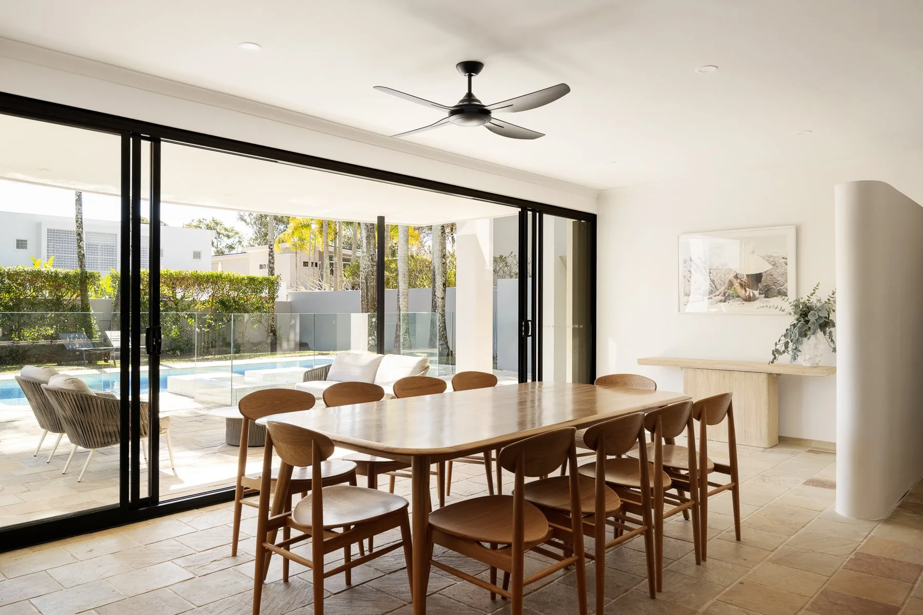 A dining area with a wooden table and chairs beside large glass doors.