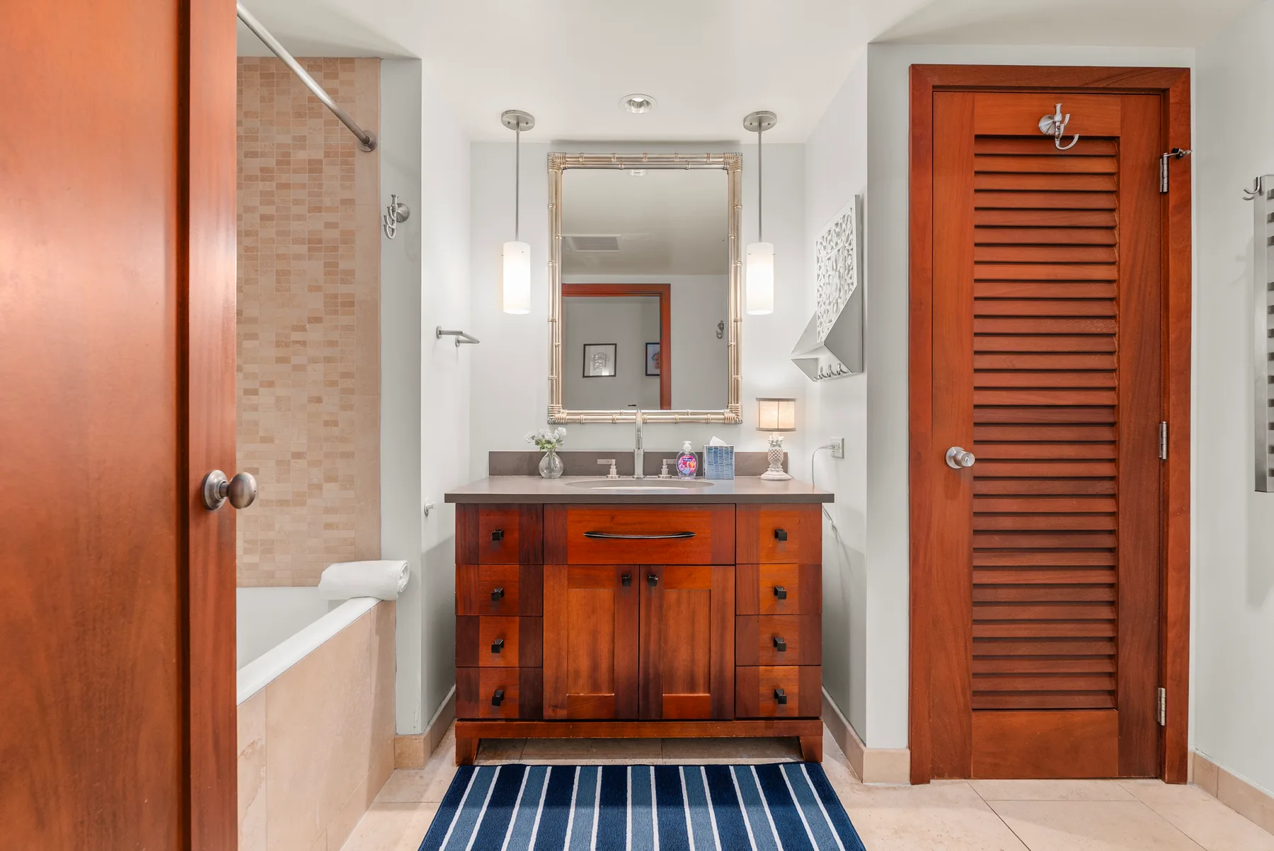Un baño con un tocador de madera, un espejo y una bañera.