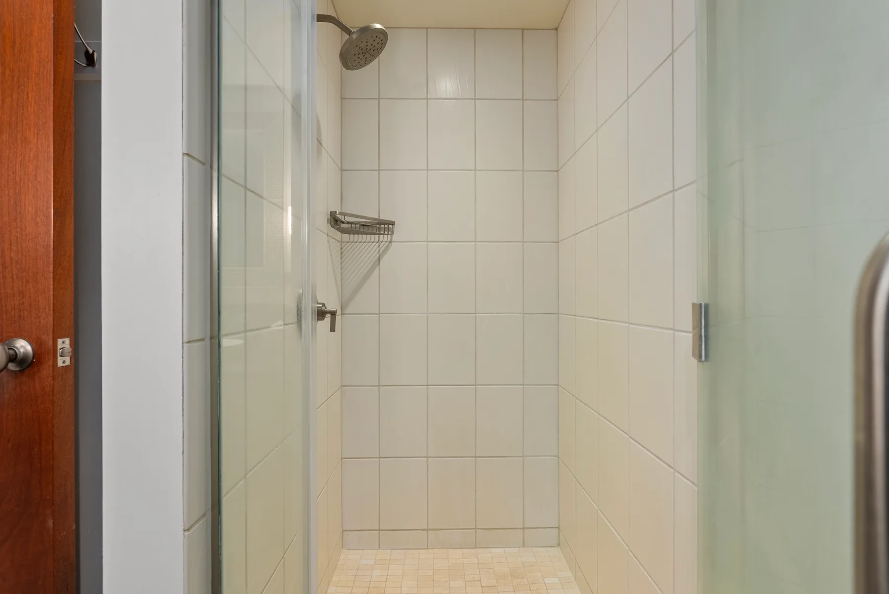 Una zona de ducha con azulejos, un cabezal de pared y paneles de vidrio.