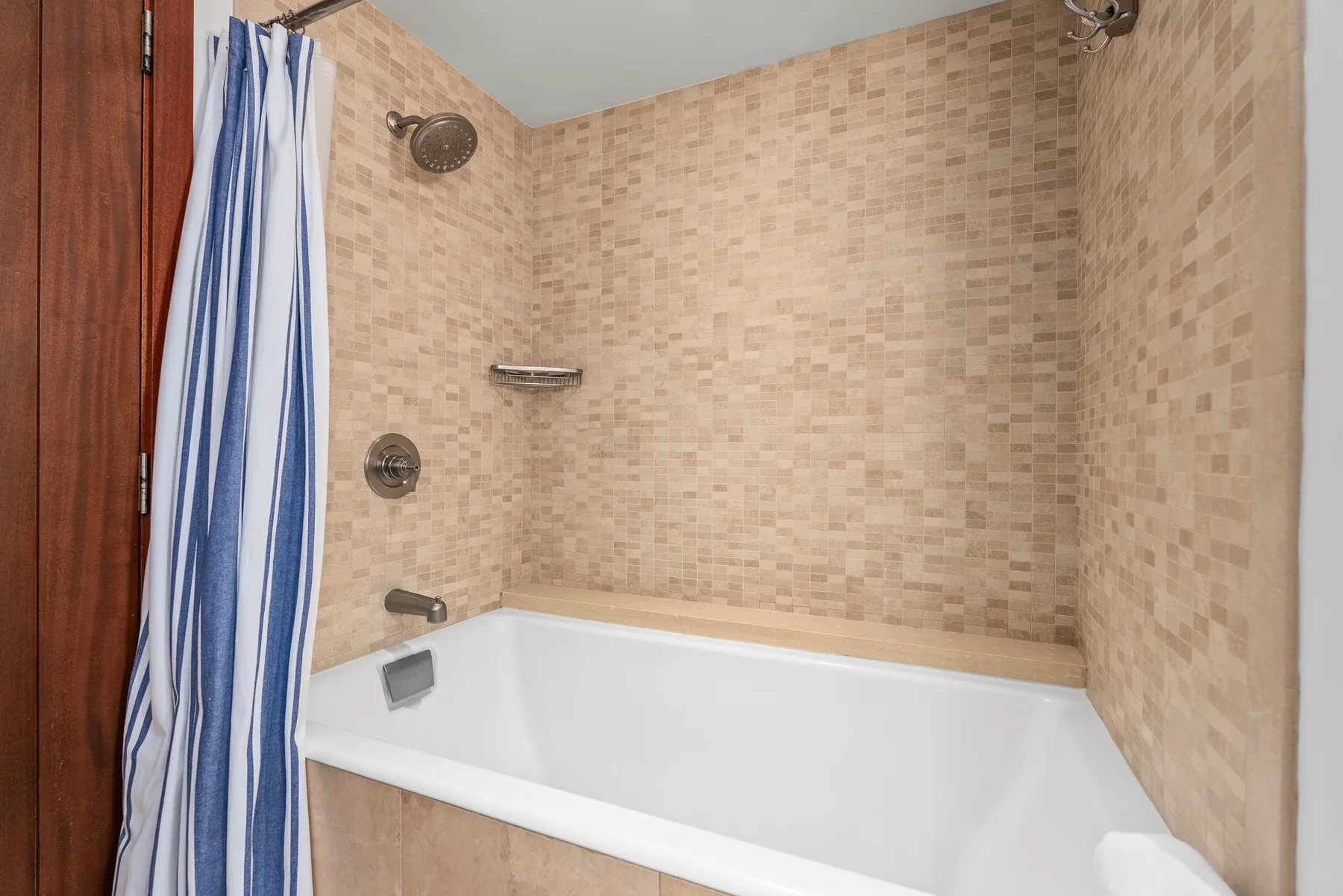 Un baño con azulejos, bañera y cortina de ducha azul y blanca.