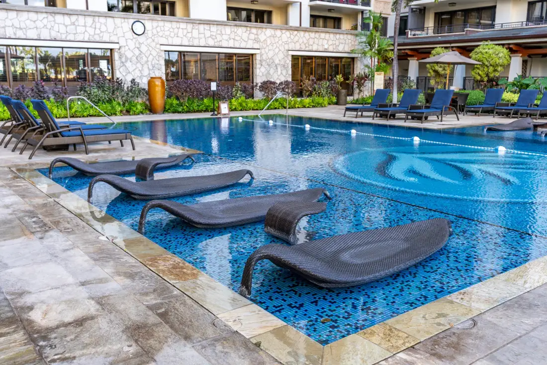 Una piscina al aire libre con tumbonas sumergidas y asientos alrededor.