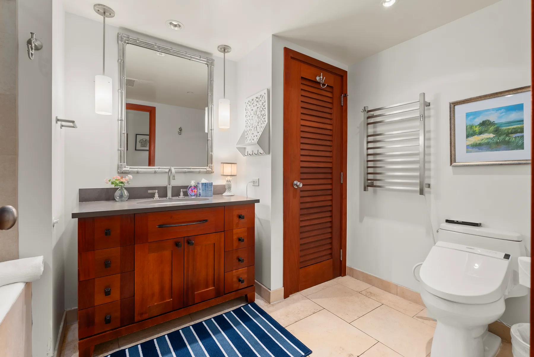Un baño luminoso cuenta con un tocador de madera, un espejo y un inodoro.