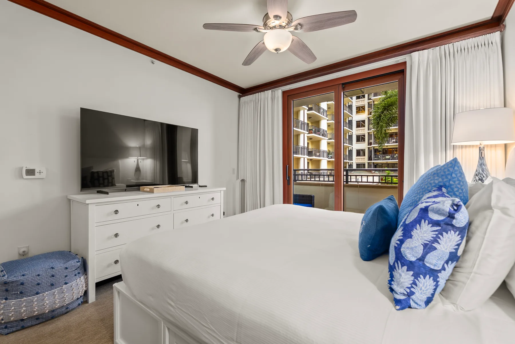Un dormitorio con una cama grande, un televisor y puertas de vidrio que dan a un balcón.