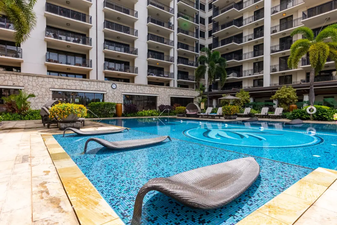 Una piscina está en un patio rodeado de balcones de apartamentos.