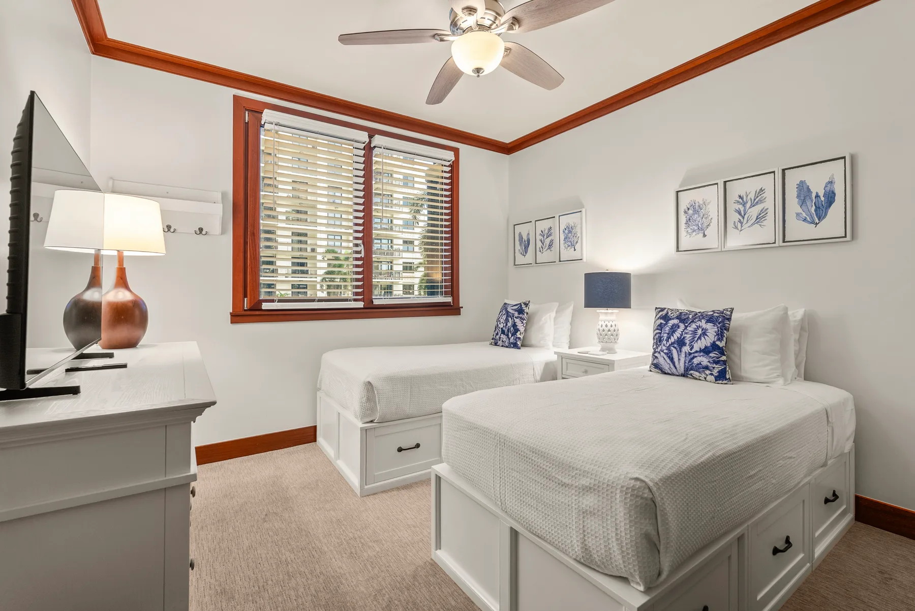 Un dormitorio luminoso con dos camas, ropa de cama blanca y láminas botánicas enmarcadas.
