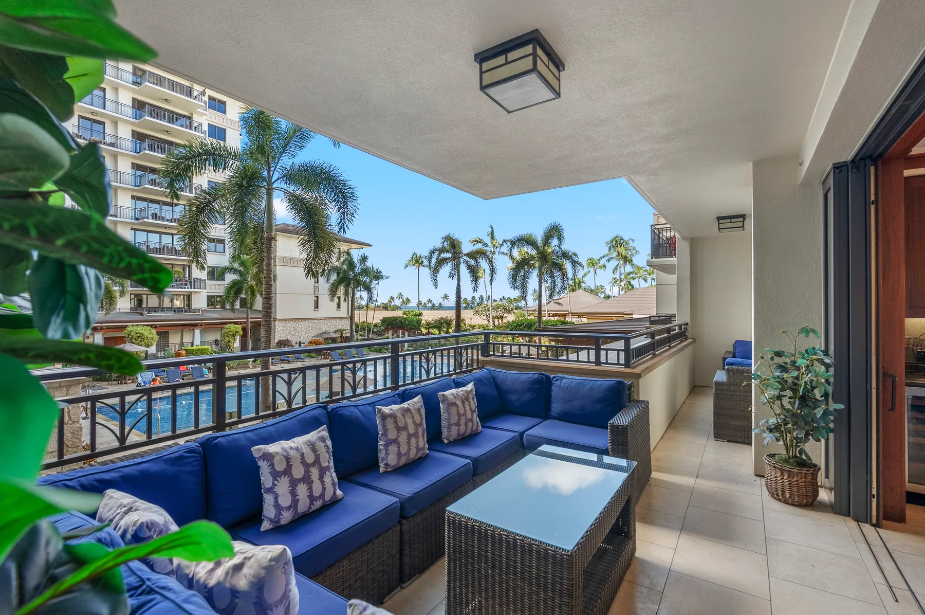 Una terraza cubierta con asientos azules y vistas a palmeras.