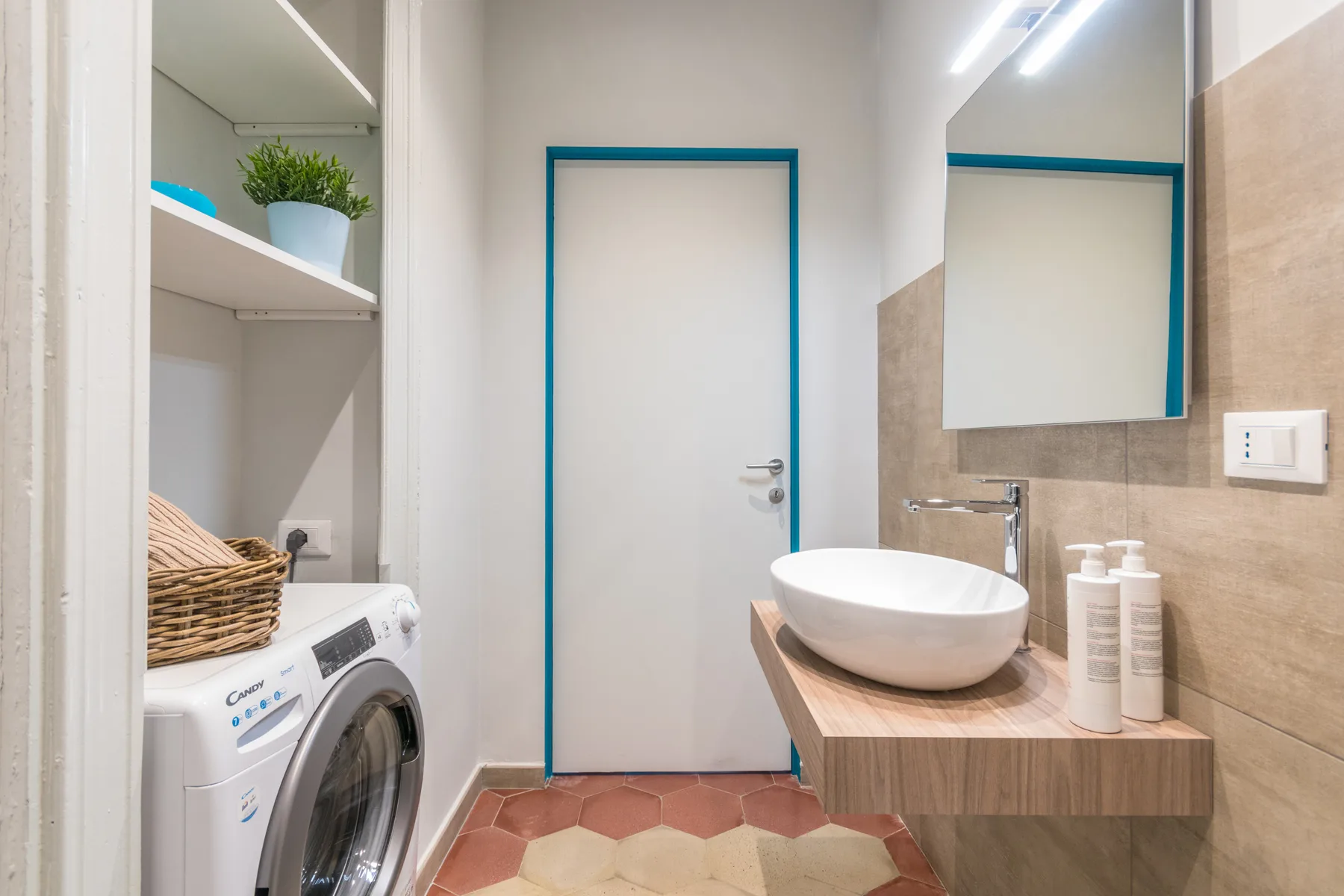 A bathroom with a vessel sink and a washing machine beside built-in shelves.