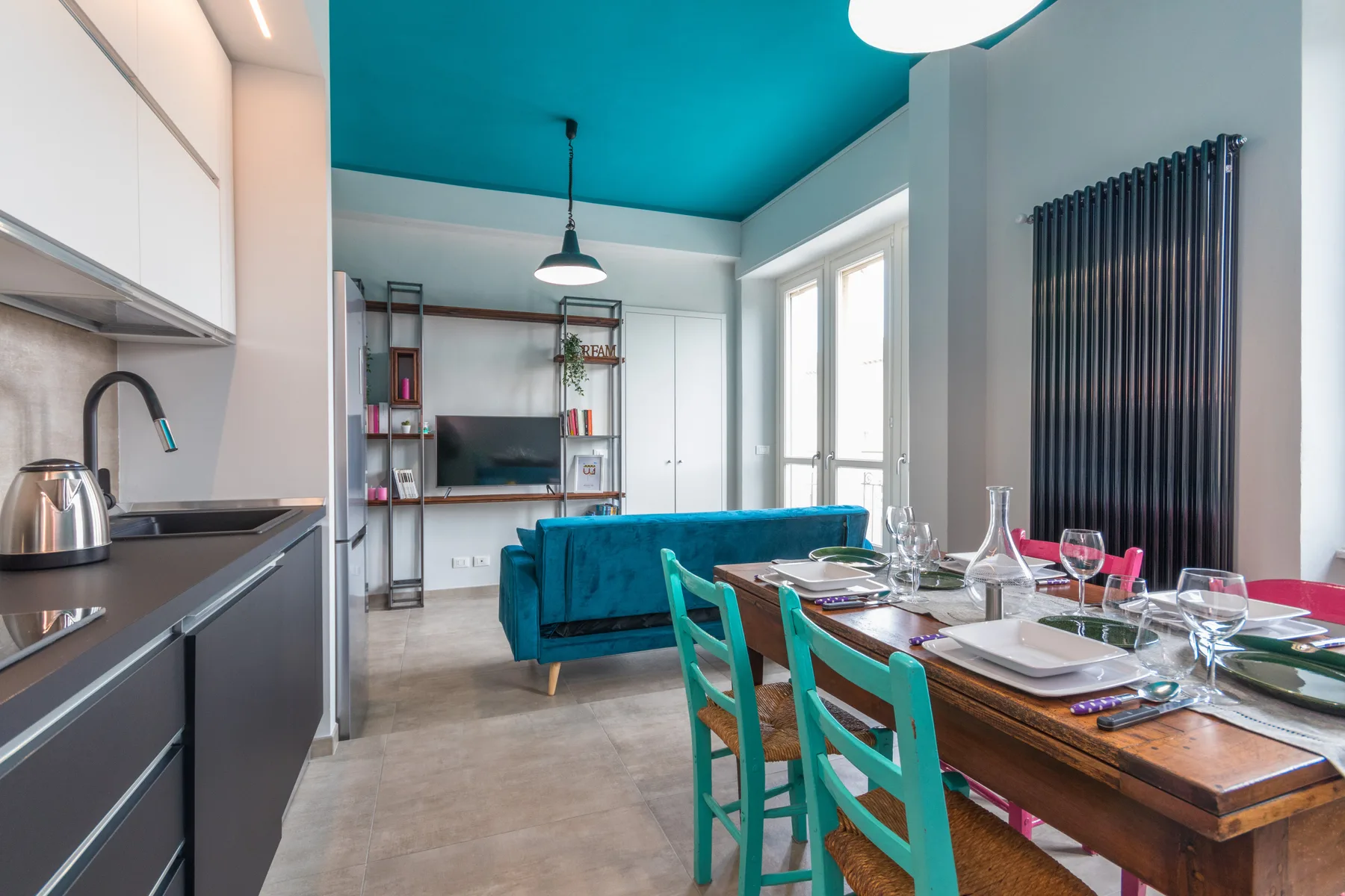 An open-plan kitchen and dining area with turquoise seating and a set table.